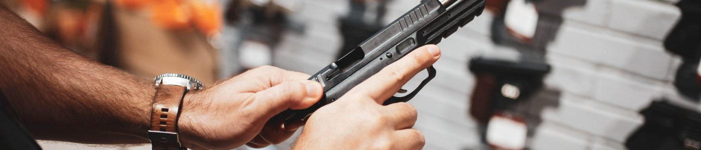 Man choosing new handgun at showcase in gun shop. Male person buying pistol for security in weapon store, selfdefence and sport shooting hobby